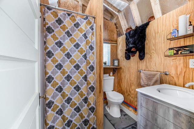 bathroom featuring vanity, wood walls, toilet, and vaulted ceiling