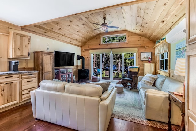 living room with dark hardwood / wood-style flooring, a wood stove, ceiling fan, and wooden walls