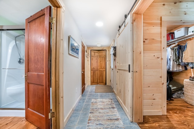 corridor with wood-type flooring and a barn door