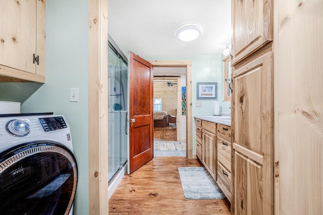 washroom with washer / dryer, light wood-type flooring, and cabinets