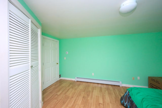 unfurnished bedroom featuring a baseboard radiator and light wood-type flooring