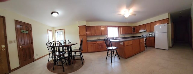 kitchen with light tile patterned floors, a center island, and white fridge