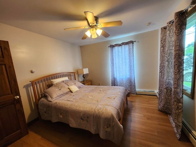 bedroom featuring ceiling fan, a baseboard heating unit, and light hardwood / wood-style floors