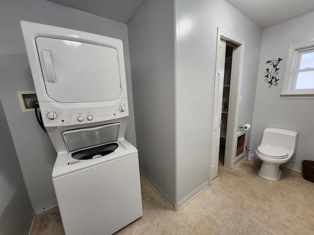 laundry area with light tile patterned floors and stacked washer / dryer