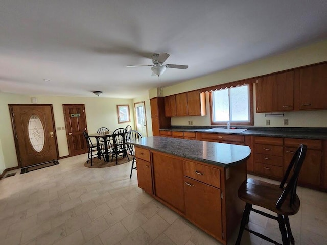 kitchen featuring ceiling fan, a breakfast bar, sink, a center island, and light tile patterned flooring