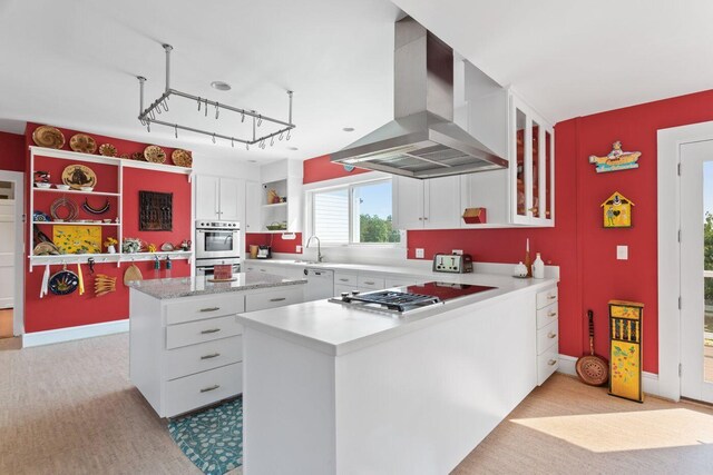 kitchen featuring stainless steel appliances, sink, kitchen peninsula, ventilation hood, and white cabinetry