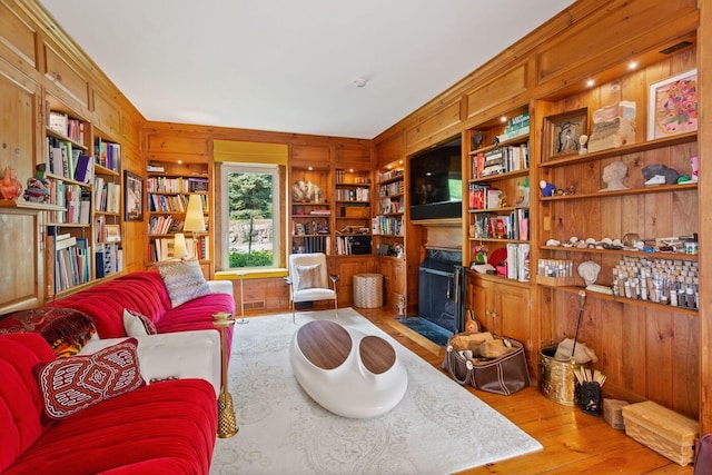 living room featuring wood walls, built in shelves, and hardwood / wood-style floors