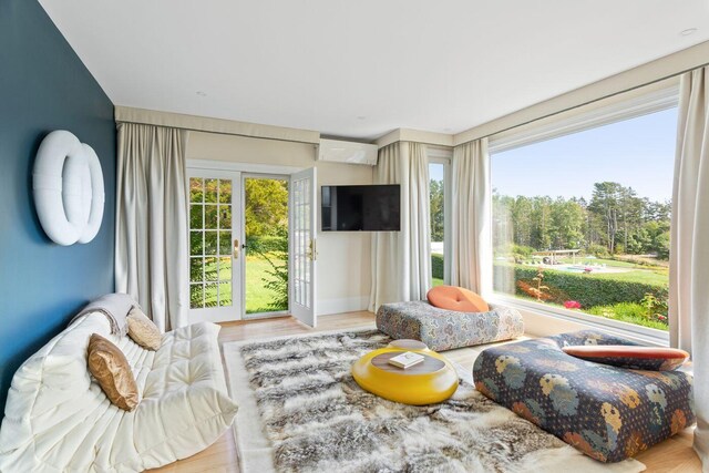 living room featuring a wall mounted AC and light hardwood / wood-style floors