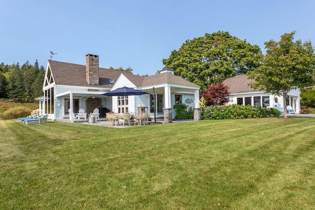 rear view of property with a patio and a lawn