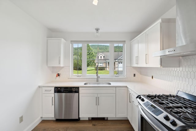 kitchen featuring white cabinetry, dark wood-type flooring, appliances with stainless steel finishes, and wall chimney range hood