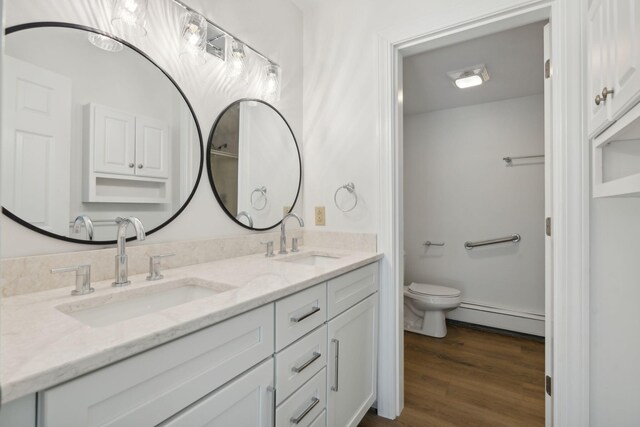 bathroom featuring hardwood / wood-style floors, baseboard heating, toilet, and dual bowl vanity