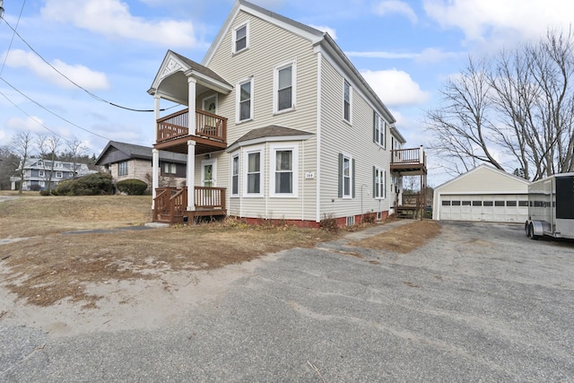 view of front of home with a garage, a balcony, and an outbuilding