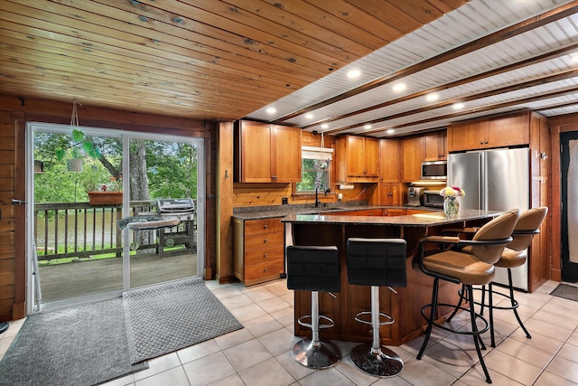 kitchen with a kitchen island, appliances with stainless steel finishes, sink, light tile patterned floors, and wood ceiling