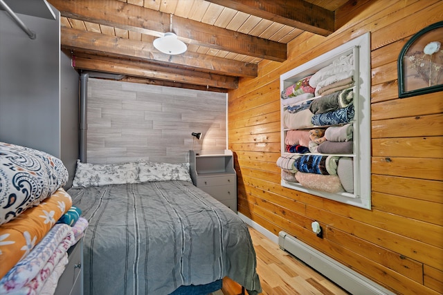 bedroom with baseboard heating, wooden walls, wood-type flooring, wooden ceiling, and beamed ceiling