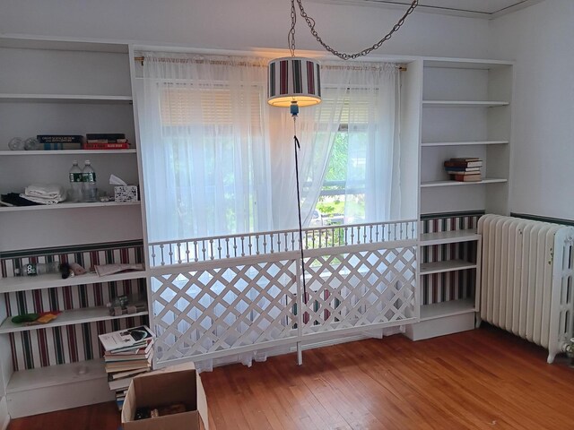 interior space with wood-type flooring, radiator, and crown molding