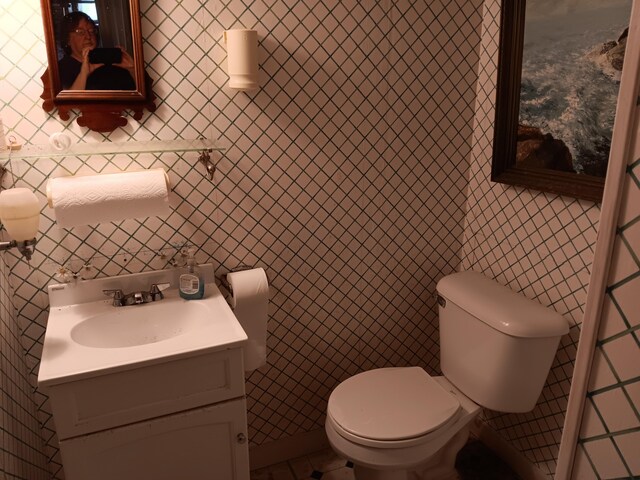 bathroom featuring tile walls, toilet, and vanity