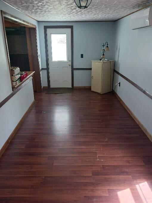 interior space with a wall mounted air conditioner, a textured ceiling, and wood-type flooring