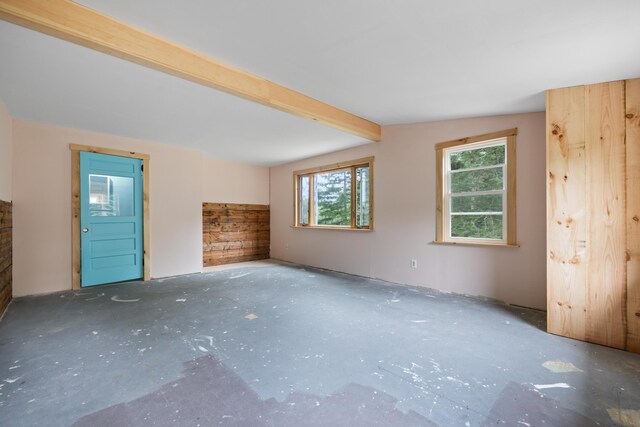 unfurnished living room with lofted ceiling with beams