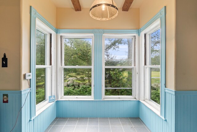 unfurnished sunroom with beamed ceiling and plenty of natural light