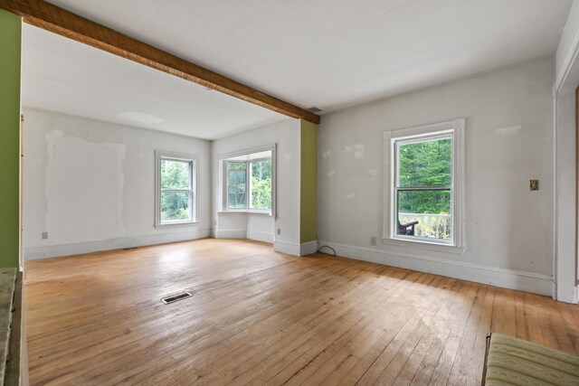 spare room featuring beamed ceiling and light wood-type flooring