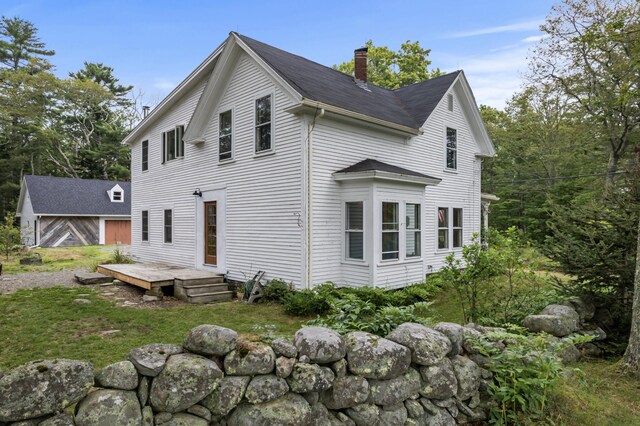 rear view of house featuring a deck and a lawn