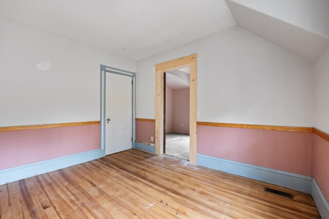 spare room with vaulted ceiling and hardwood / wood-style floors