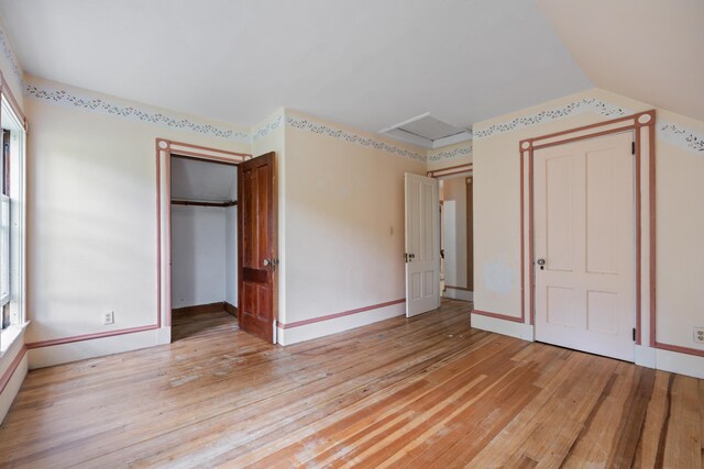 unfurnished bedroom with multiple windows, hardwood / wood-style flooring, and a closet