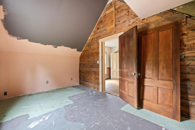 bonus room with wood walls and vaulted ceiling