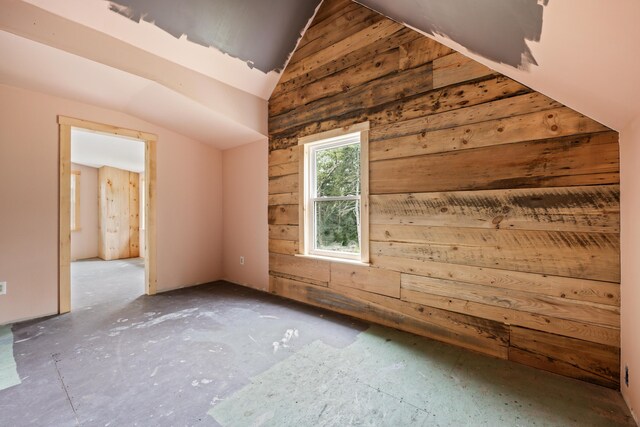 bonus room with wood walls and lofted ceiling