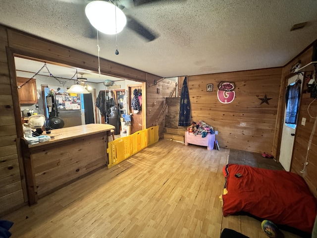 interior space with light wood-type flooring, a textured ceiling, and wooden walls