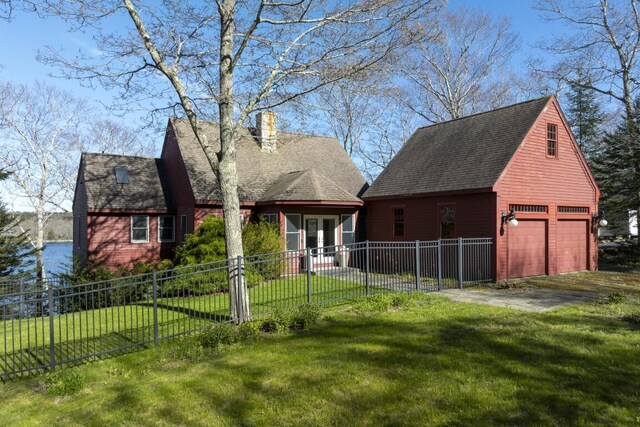 rear view of property with a garage and a lawn