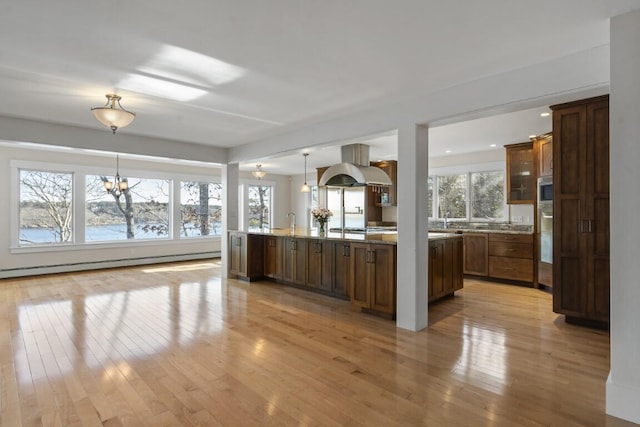 kitchen with a baseboard radiator, island range hood, light wood-type flooring, and decorative light fixtures