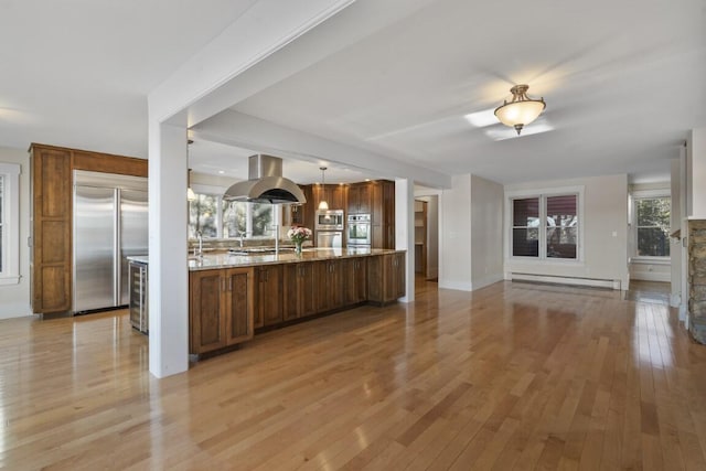 kitchen featuring a baseboard radiator, island exhaust hood, light hardwood / wood-style floors, stainless steel appliances, and light stone countertops