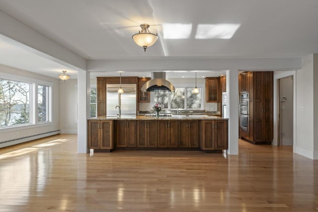 kitchen with hanging light fixtures, wood-type flooring, baseboard heating, and stainless steel built in refrigerator