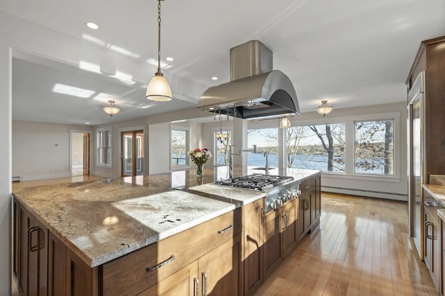 kitchen with light stone countertops, a baseboard radiator, island exhaust hood, and a water view