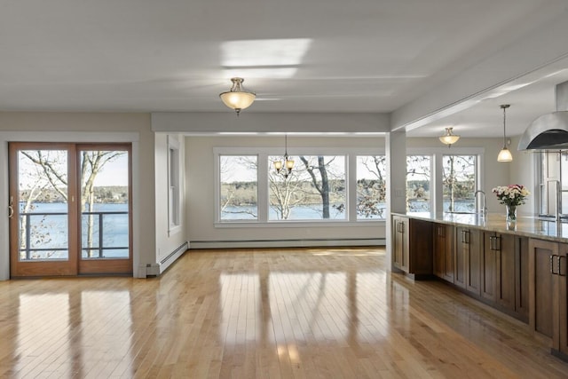 interior space with a water view, baseboard heating, and light wood-type flooring