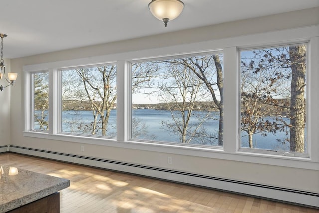 unfurnished dining area featuring a water view, a notable chandelier, hardwood / wood-style flooring, and a baseboard heating unit