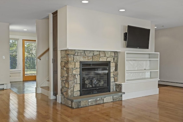 unfurnished living room featuring a baseboard radiator, hardwood / wood-style floors, and a fireplace