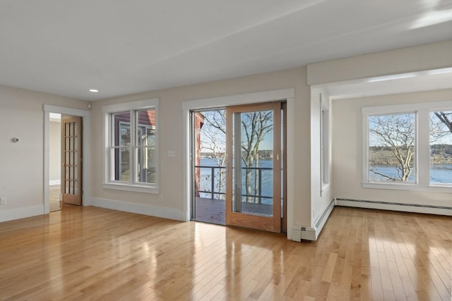 doorway featuring a baseboard radiator, a water view, a healthy amount of sunlight, and light wood-type flooring