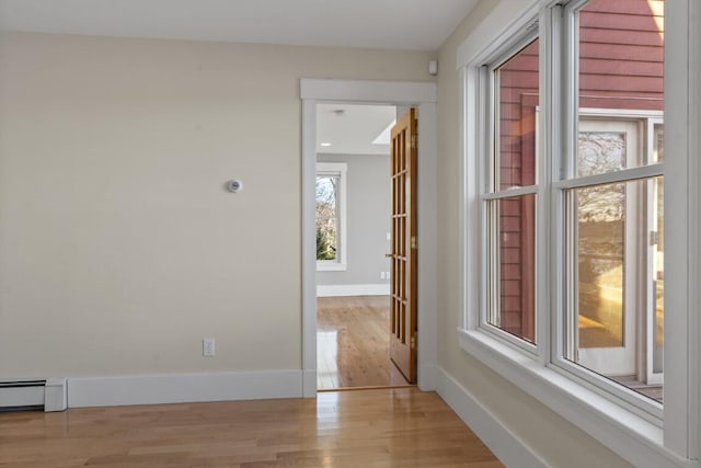 corridor featuring baseboard heating and light wood-type flooring