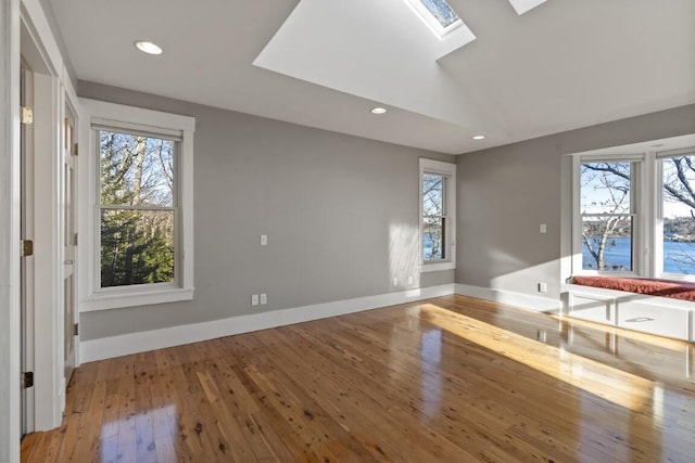 interior space featuring hardwood / wood-style flooring, a healthy amount of sunlight, and vaulted ceiling with skylight