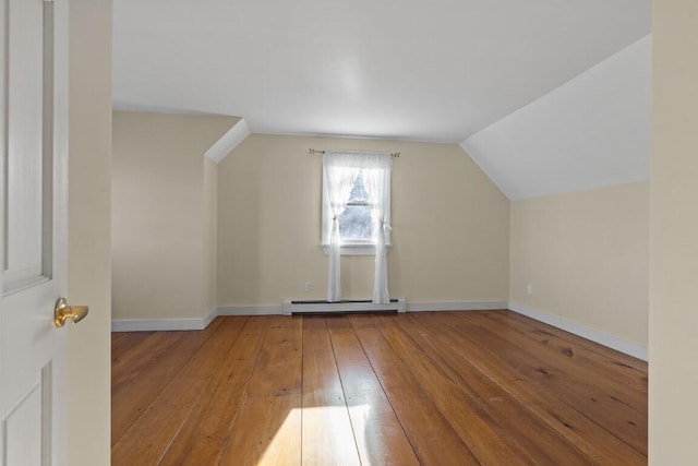 additional living space with lofted ceiling, a baseboard heating unit, and hardwood / wood-style flooring