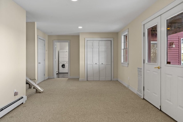 unfurnished bedroom with light carpet, a baseboard radiator, and stacked washer / dryer