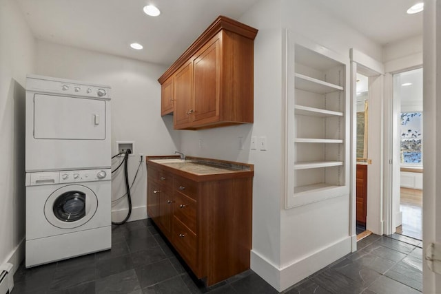 washroom featuring built in features, stacked washer / dryer, sink, cabinets, and baseboard heating