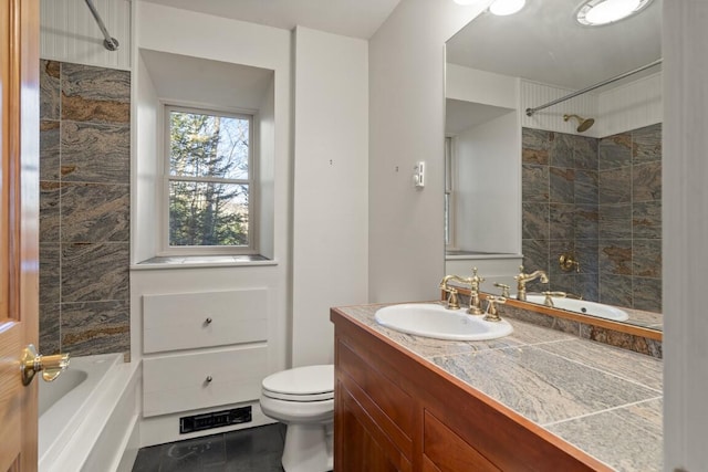 full bathroom with tiled shower / bath, vanity, and toilet