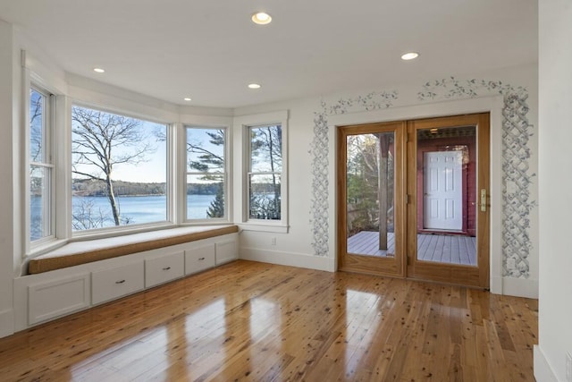 doorway to outside with a water view and light hardwood / wood-style flooring