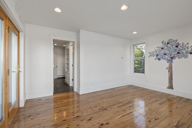 empty room with wood-type flooring and baseboard heating