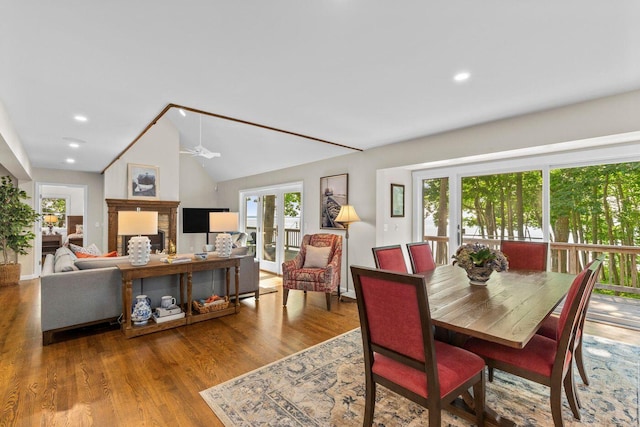 dining area with hardwood / wood-style flooring, vaulted ceiling, a fireplace, and ceiling fan