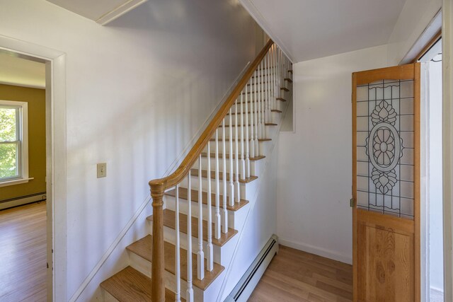 stairway featuring a baseboard radiator and wood-type flooring