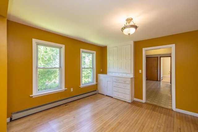 spare room with a baseboard heating unit and light hardwood / wood-style floors